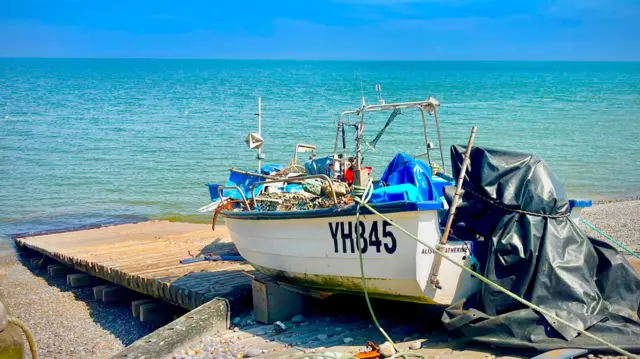 Boat pictured by crystal blue waters in Sheringham, Norfolk, with clear blue skies overhead