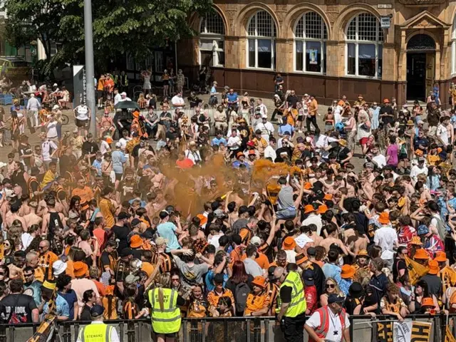 Fans set off orange flares in Queen Victoria Square as the crowds increase.