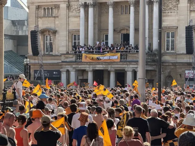 Hundreds of Hull City fans watch as the players life a silver trophy on the balcony of a city hall