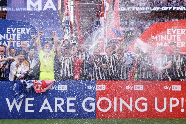 Notts County players celebrate their play-off win over Salford as the champagne goes off