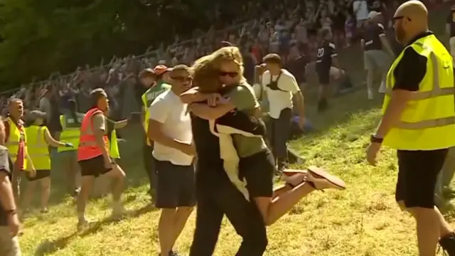Tom is being hugged by a woman at the bottom of the hill.