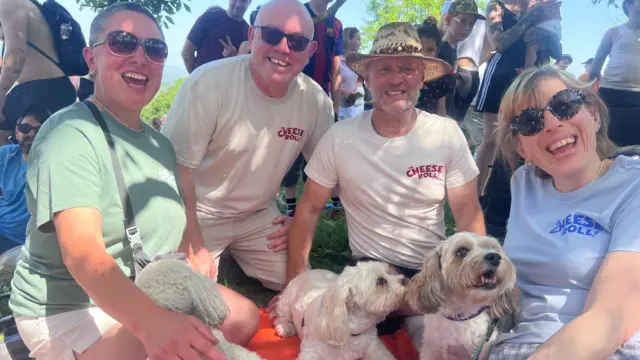 Watchers of the event smile, while three dogs sit on a blanket with them.