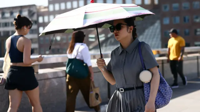 A woman shields herself from the sun with an umbrella