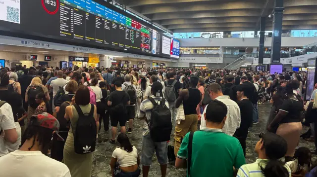 A large crowd of people waiting for train updates at London Euston station