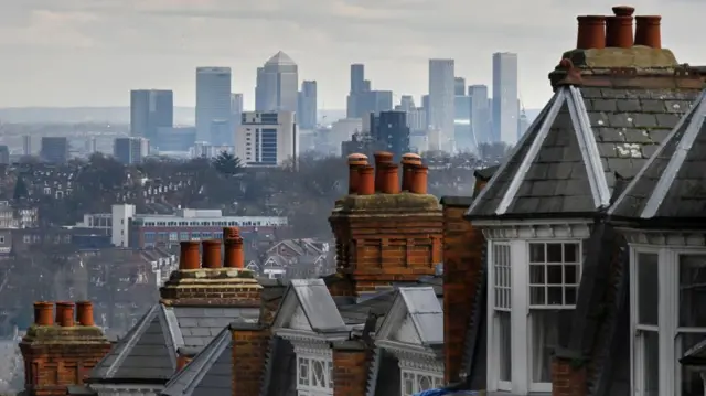 A view of a London city skyline with terraced homes in the foreground.