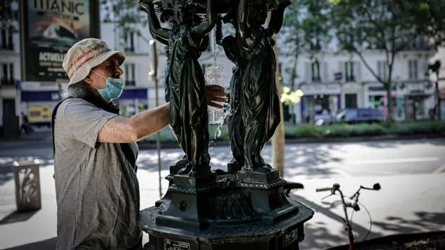 A man fills a glass of water at a public fountain in the Montparnasse district of Paris on May 25, 2026, as French weather service Météo-France placed the capital under yellow alert amid an exceptionally early heatwave, with temperatures forecast to reach 35C across the region.
