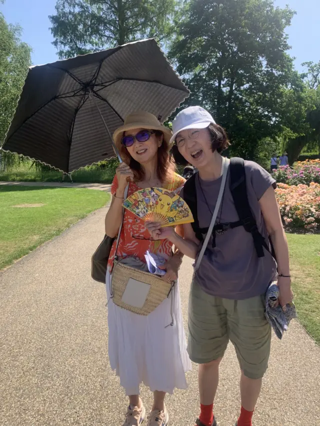 Two ladies in Regent's Park with an umbrella smiling in the sun