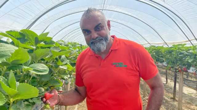 A man holding a strawberry in a red t shirt