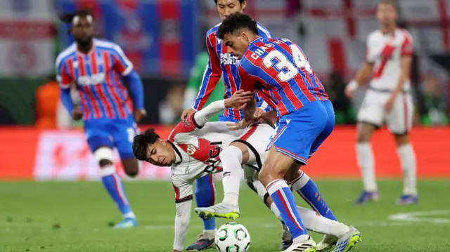 Ilias Akhomach of Rayo Vallecano is challenged by Daichi Kamada and Chadi Riad