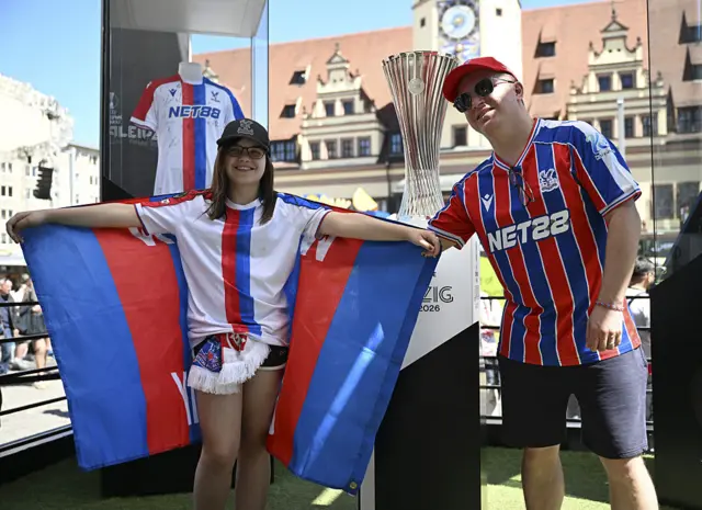 Crystal Palace fans posing in front of the Conference League trophy