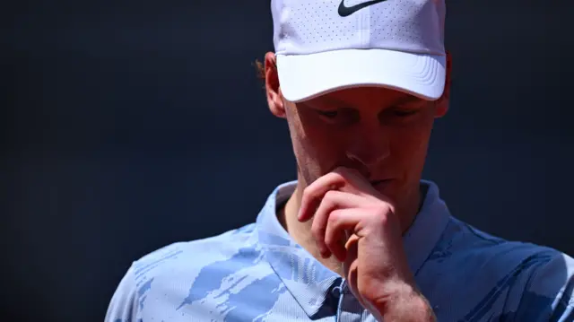 Jannik Sinner wipes his face