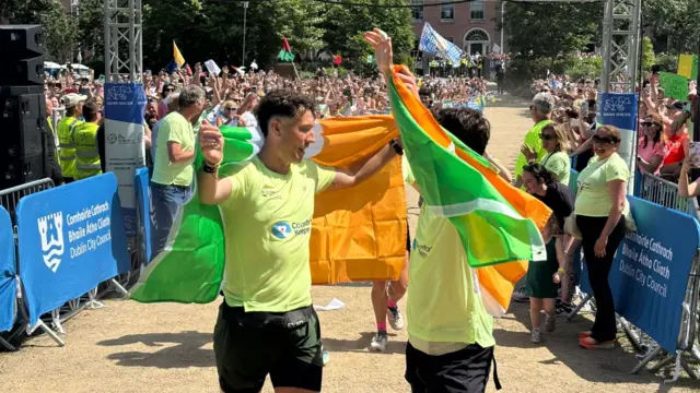 The brothers are about to hug holding Irish flags in each hand