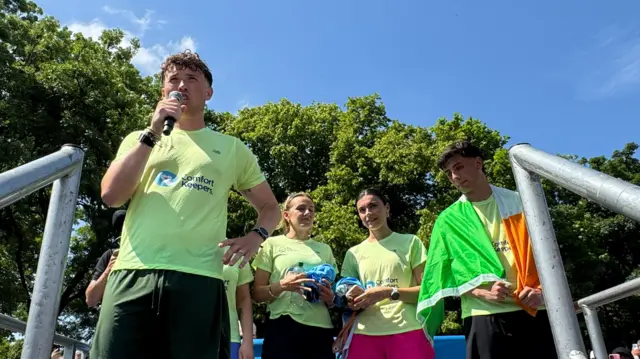 man with microphone, and two women and a man next to him