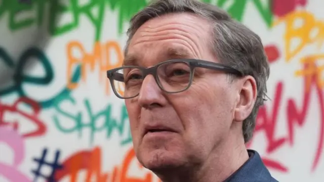 A file photo of Alan Milburn - he is standing in front of a wall with graffiti on it