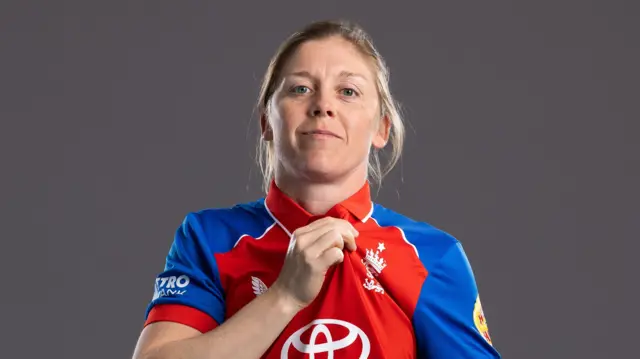 Heather Knight lifting the badge on her England shirt