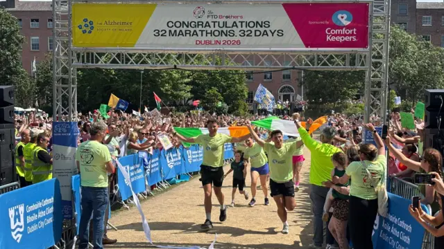 The brothers are running across the finish line holding Irish flags above their heads