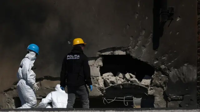 Romanian law enforcement officers work on the site of an explosion at a residential block of flats where a drone hit.