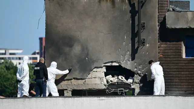 Police and forensic investigators examine the location of impact after a Russian drone struck an apartment building in Galati