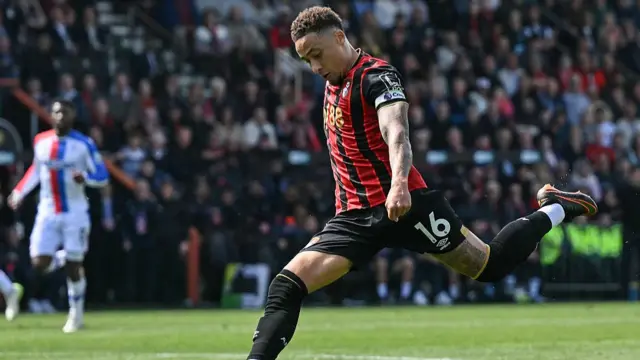 Marcus Tavernier kicks a ball in red and black stripe kit
