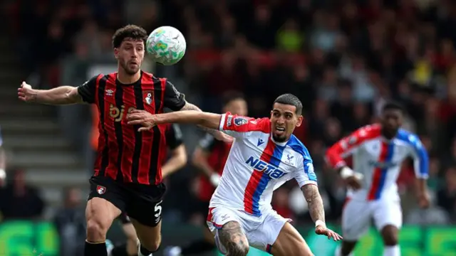 Senesi in black and red Bournemouth kit challenging a Crystal Palace player in white kit with a blue and red stripe