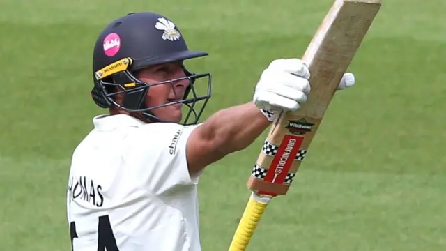 Adam Thomas celebrates reaching a fifty