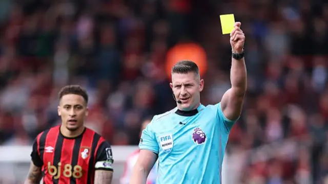 Referee holds a yellow card