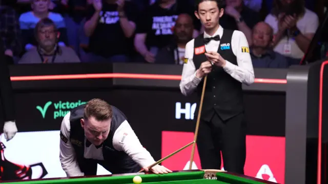 Shaun Murphy and Wu Yize look at the table
