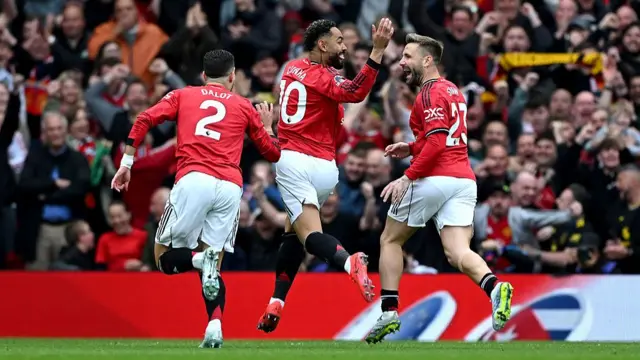 Manchester United players celebrate a goal in red kit