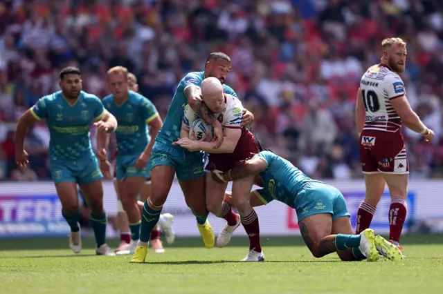 Liam Farrell of Wigan Athletic is tackled by Tom Amone and Elliot Minchella of Hull Kingston Rovers