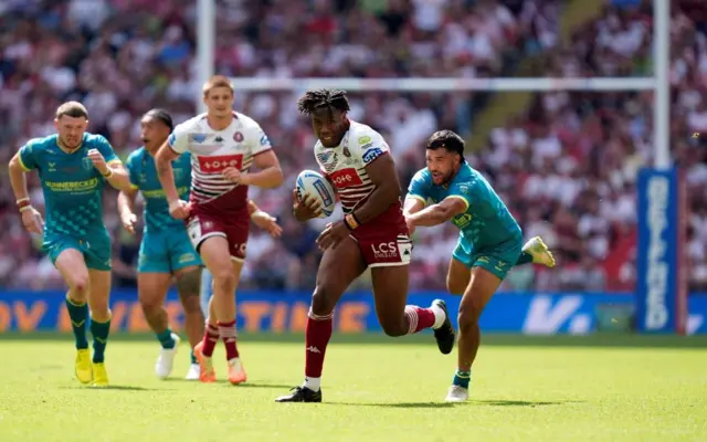 Wigan Warriors' Junior Nsemba (second right) breaks a tackled from Hull KR' Peta Hiku (right)
