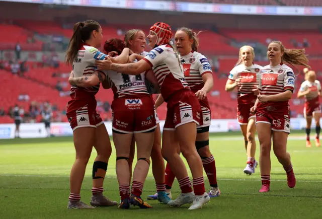 Wigan celebrate scoring a try against St Helens.