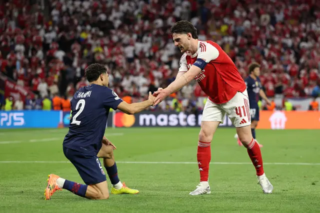 Achraf Hakimi of Paris Saint-Germain is helped to his feet by Declan Rice