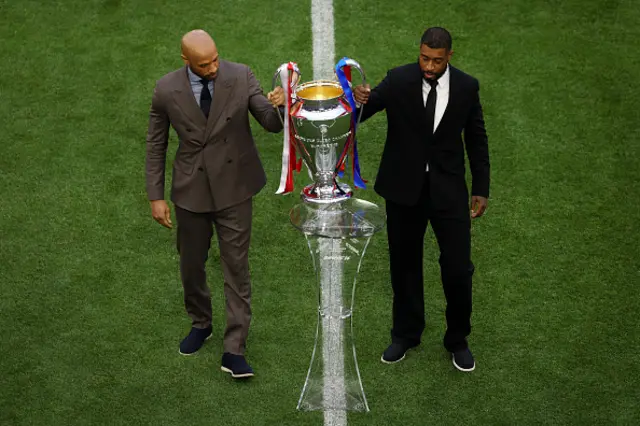 Thierry Henry and Presnel Kimpembe carry the UEFA Champions League trophy onto the pitch
