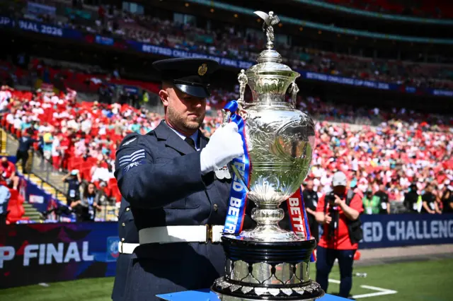 Military representatives bring the Betfred Challenge Cup out to the plinth.