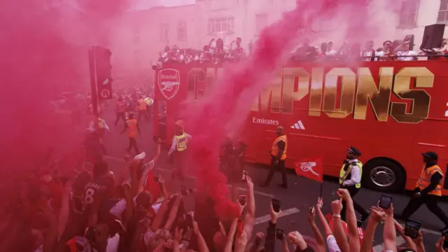 Red flares cover the view of Arsenal's victory bus