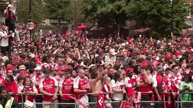 A large crowd at the side of the parade route