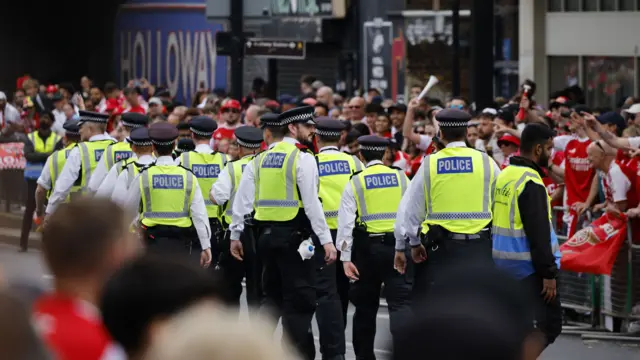 Police officers walk down the parade route which is lined with Arsenal fans