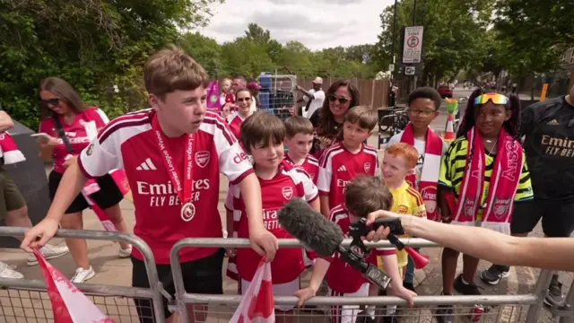 Young fans speak to a BBC News reporter on the parade