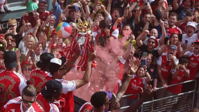 Saliba holds the trophy up with the crowd behind