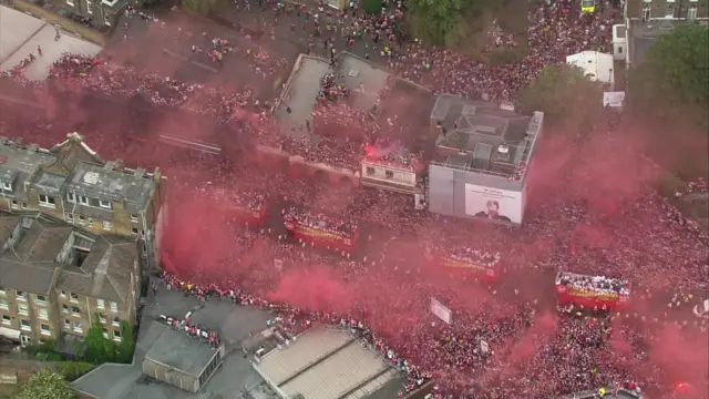 Fans stand on rooftops as seen from the air as the parade passes