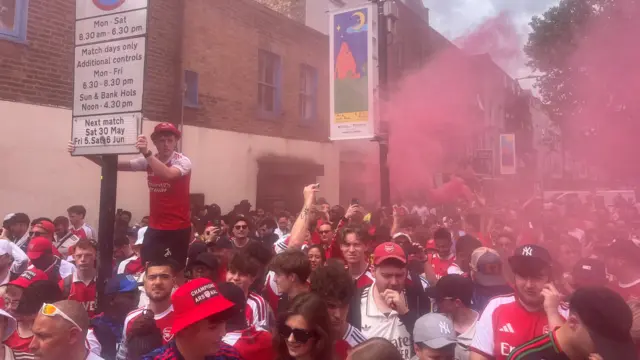 Arsenal fans on the street as red flares go off in the distance