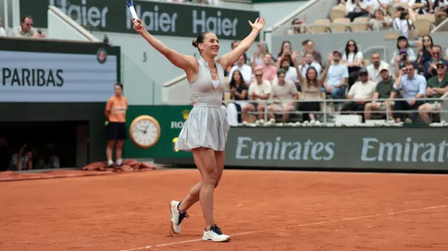 Marta Kostyuk with her arms outstretched celebrates her victory over Iga Swiatek