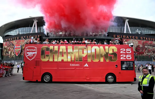 The Champions bus parked outside the Emirates Stadium with massive red flares coming from the stadium