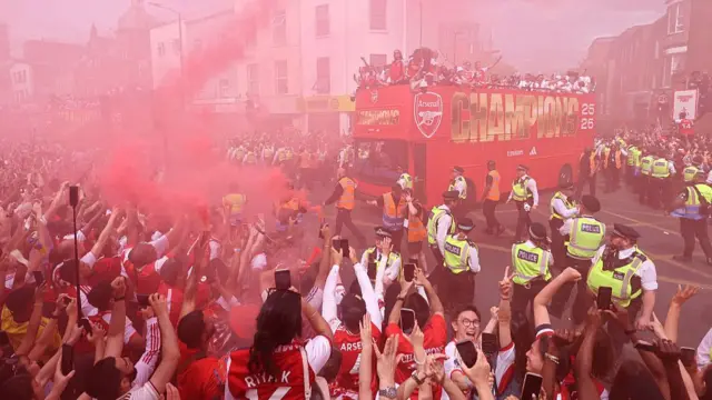 Arsenal's women's team players celebrate with their FIFA Women's Champions Cup trophy during a victory parade with the men's team around the streets near to the Emirates Stadium, in London,