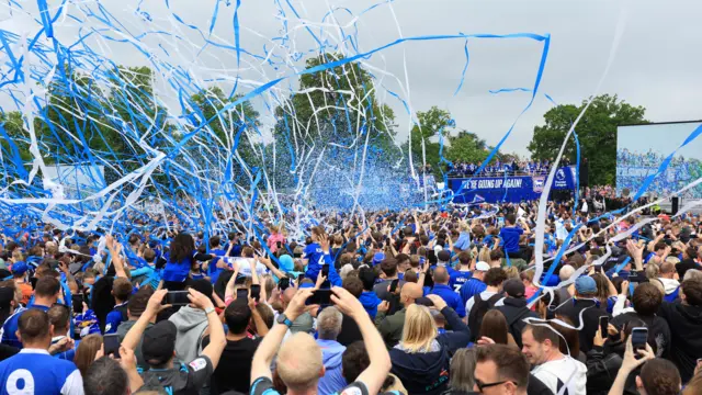 Blue and white streamers projected into the sky above fans heads at Christchurch Park