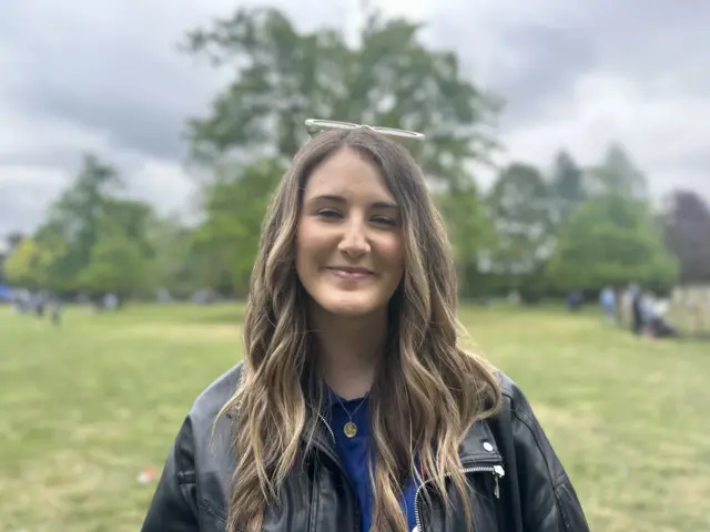 A woman with long brown hair wearing a leather jacket.