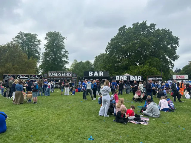 People gathered around food and drink vendors at a park