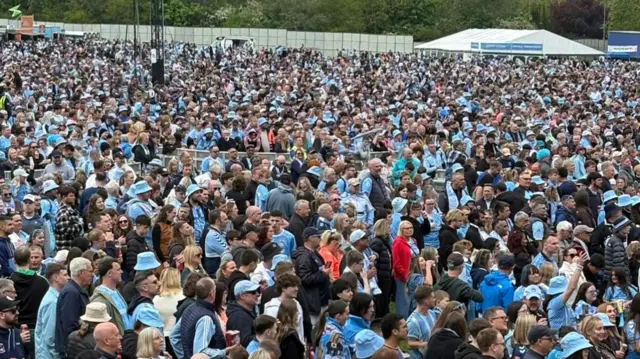 Hundreds of fans standing in a park