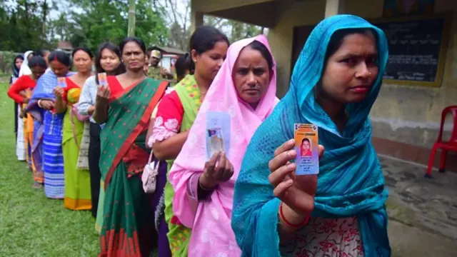 Women voters stand in a queue to cast their ballots at a polling booth in Assam's Nagaon district on 9 April.