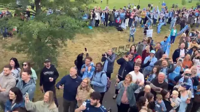 Fans looking up at the bus on a grassy area